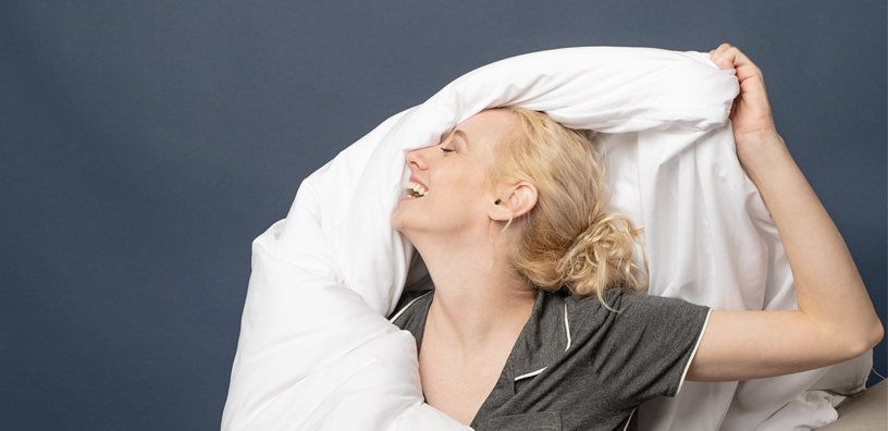 A happy woman feeling her comforter.