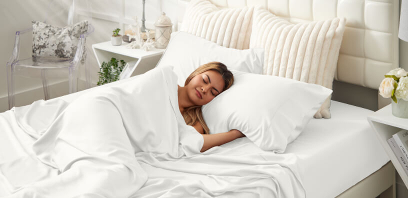 Young woman snuggled underneath bright white Cosy House duvet in a serene and inviting bedroom.