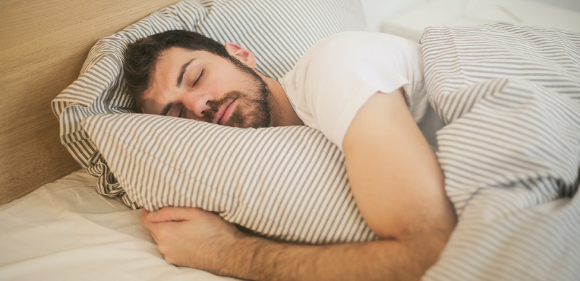 A man is sleeping well while hugging a pillow.