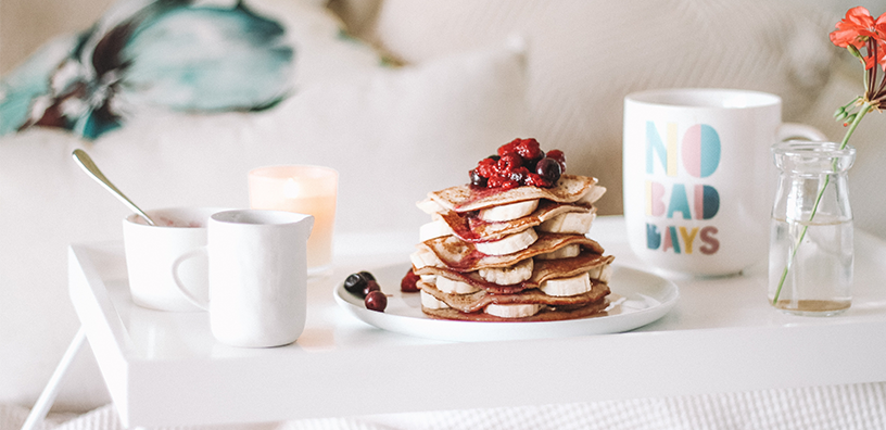 A delicious stack of pancakes topped with fresh berries, elegantly presented on a white tray.