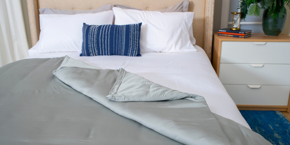 A weighted blanket on top of a well-arranged bed.