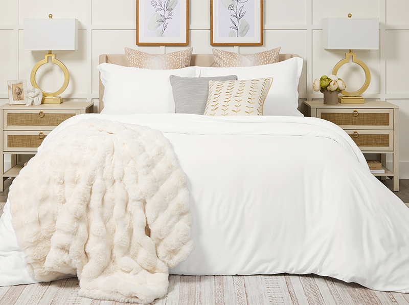 Neatly made bed with white bedding and decorative pillows in a bedroom setting.