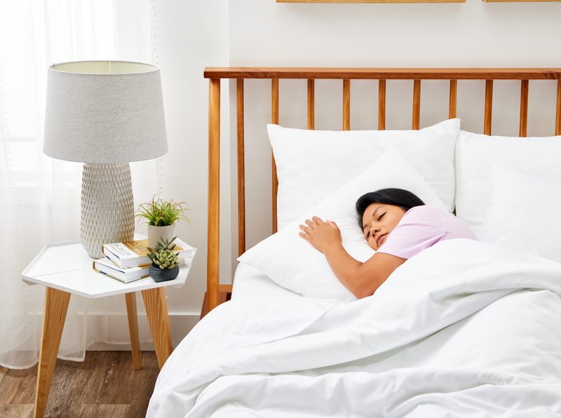 A woman peacefully sleeping, resting her head on a Cosy House Collection Everyday Down Alternative Pillow.