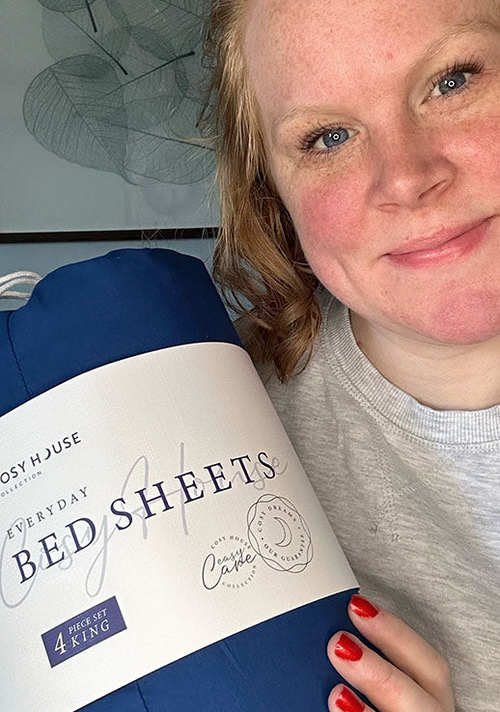 Another happy female customer is holding a packaged set of Cosy House Collectionâs Everyday Bed sheets.