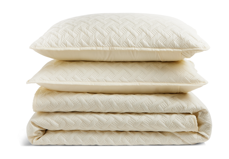 A stack of a folded quilt and pillow shams.