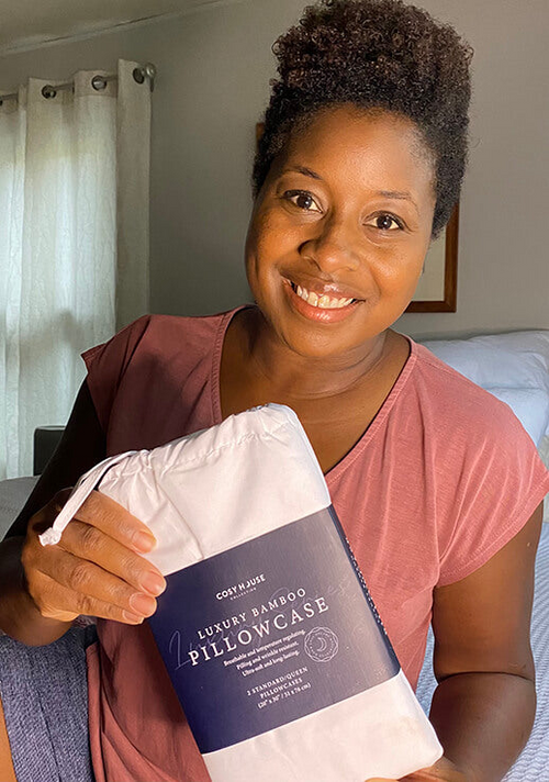 A smiling customer showing a packaged pair of Luxury pillowcases.