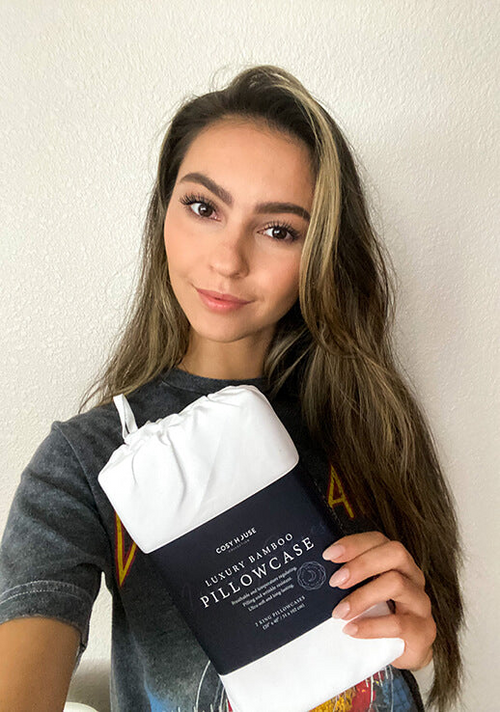A customer flexing her packaged pair of Luxury pillowcases.