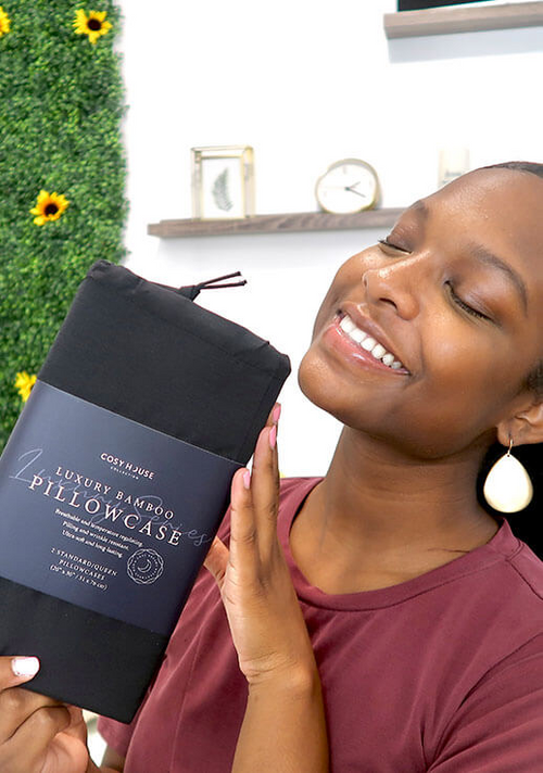 A smiling customer flexing a packaged pair of Luxury pillowcases.