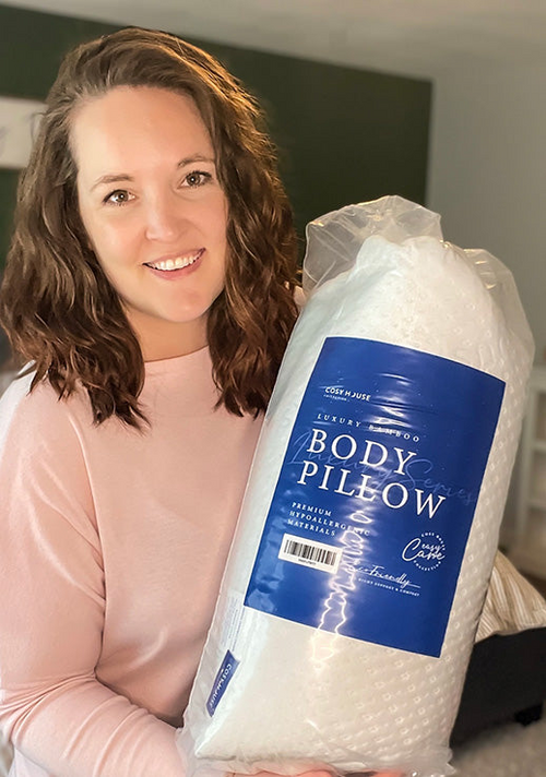 A happy customer is holding a packaged Cosy House Collection Luxury Body Pillow.