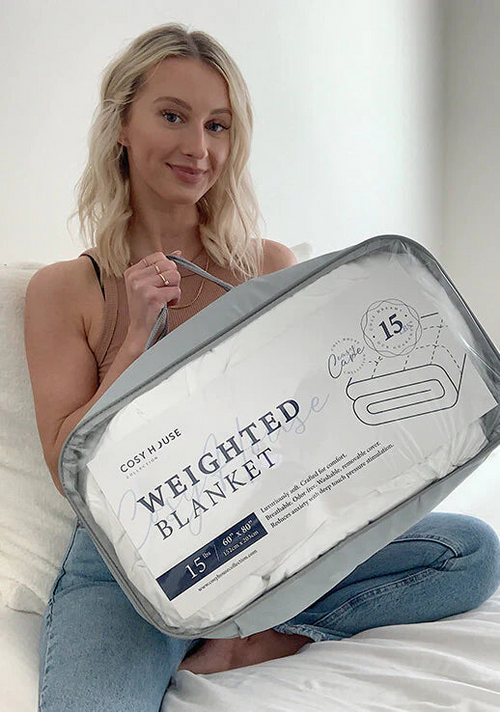 A customer sitting comfortably on her bed showing her new Weighted blanket.