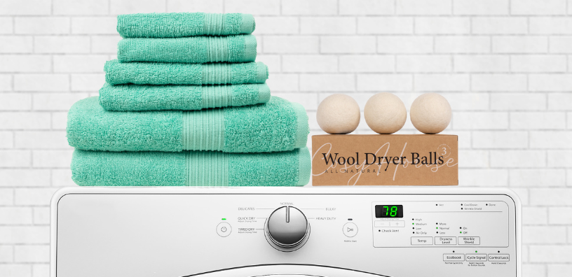 Turquoise Cosy House towels and all-natural wool dryer balls displayed on a washing machine.