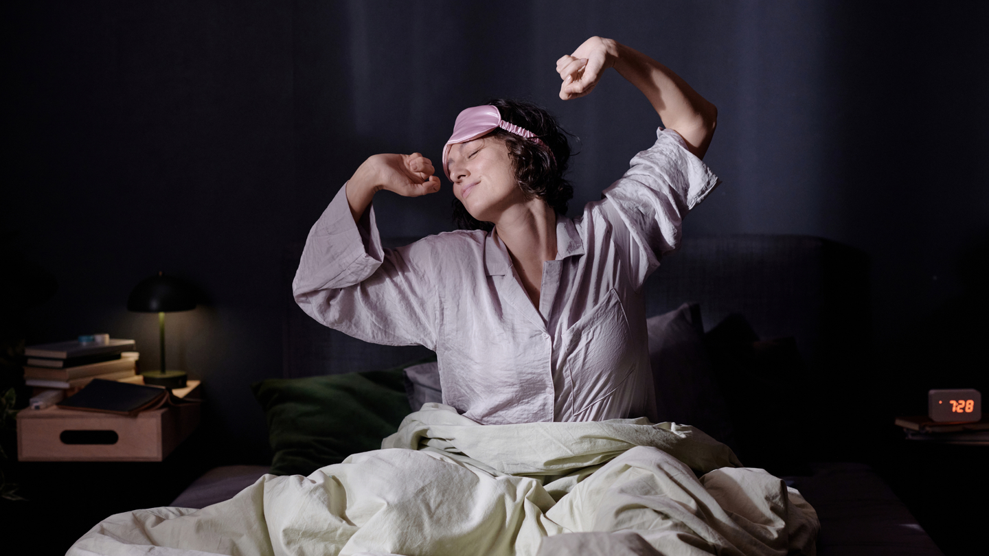 Young woman stretching in her cozy bed