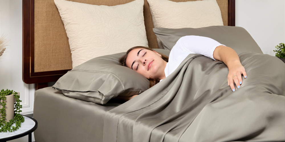 Woman asleep under grey bamboo sheets with one arm resting outside the covers.