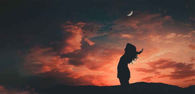 A silhouette of a person on a hill, admiring a beautiful crescent moon shining brightly above.
