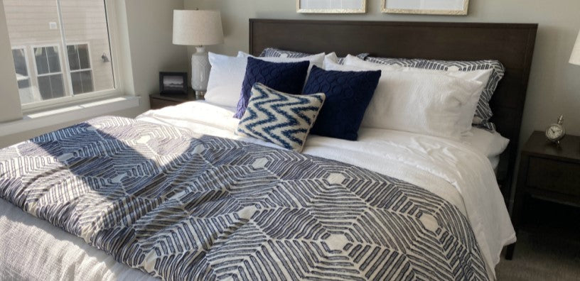 A stylish bed adorned with sheets and fluffy pillows, perfect for a restful sleep.