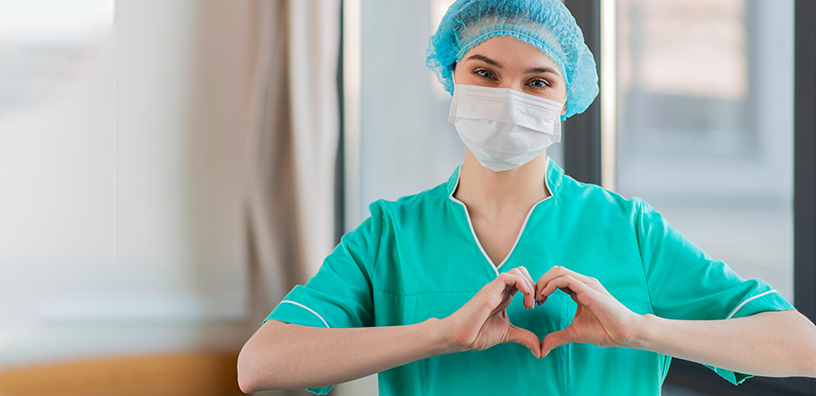 A nurse making a heart sign with both hands.