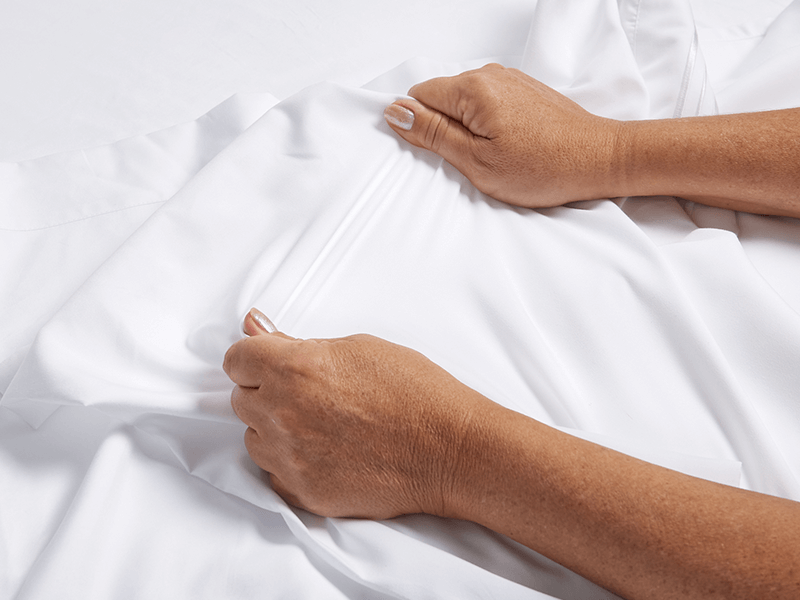 A person is stretching a Cosy House Collection sheet.