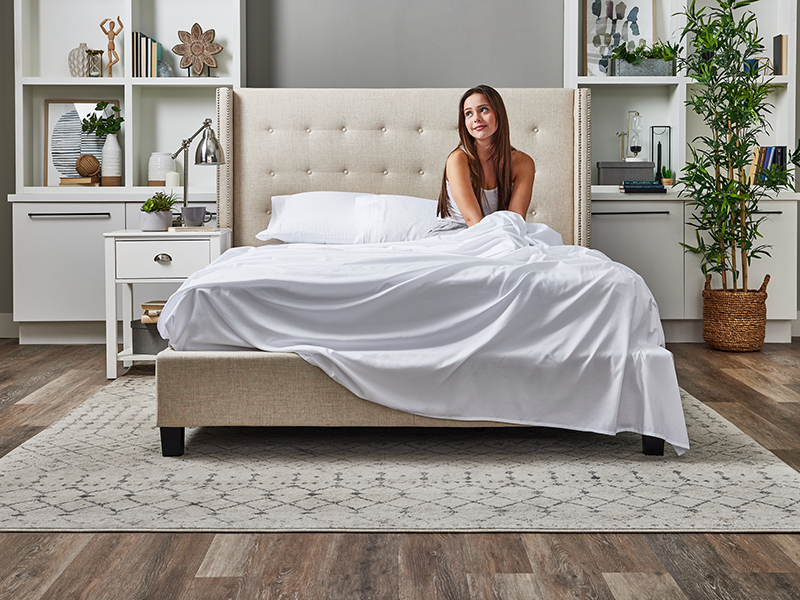 A woman is seated on a bed with Cosy House Collection bedding, exuding a sense of relaxation and tranquility.
