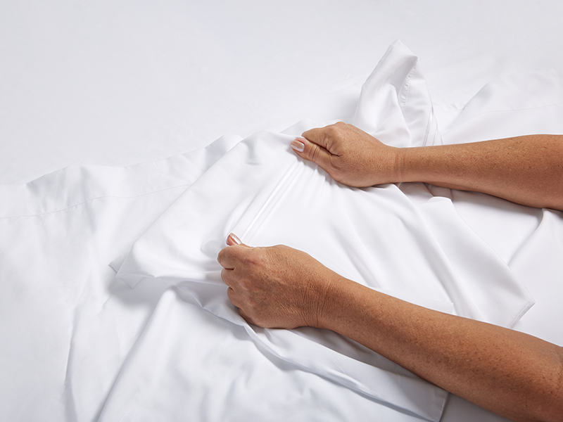 A person is stretching a Cosy House Collection sheet.