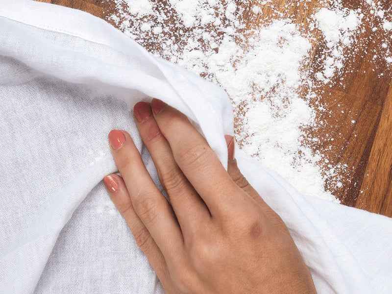 A person is using a towel to wipe spilled flour.