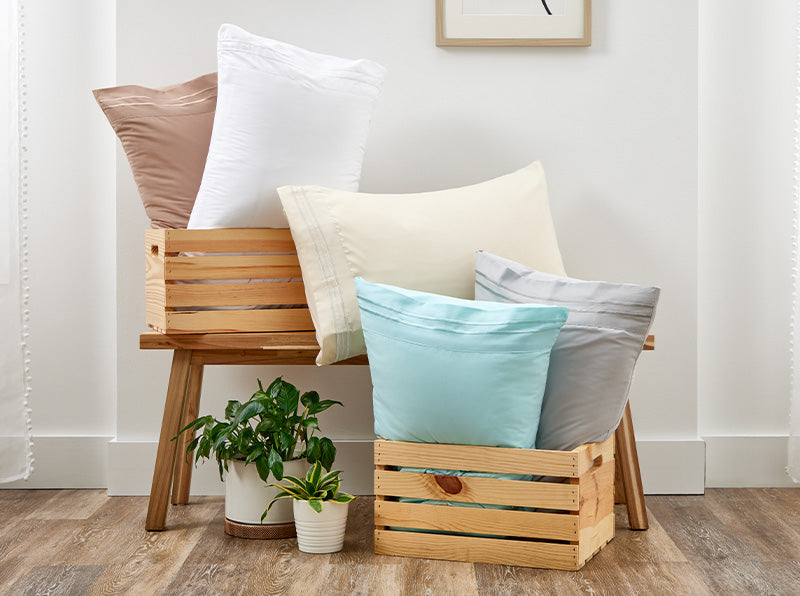 A cozy setup featuring a couple of pillows covered with Cosy House Collection’s Everyday pillowcases stacked on wooden crates.